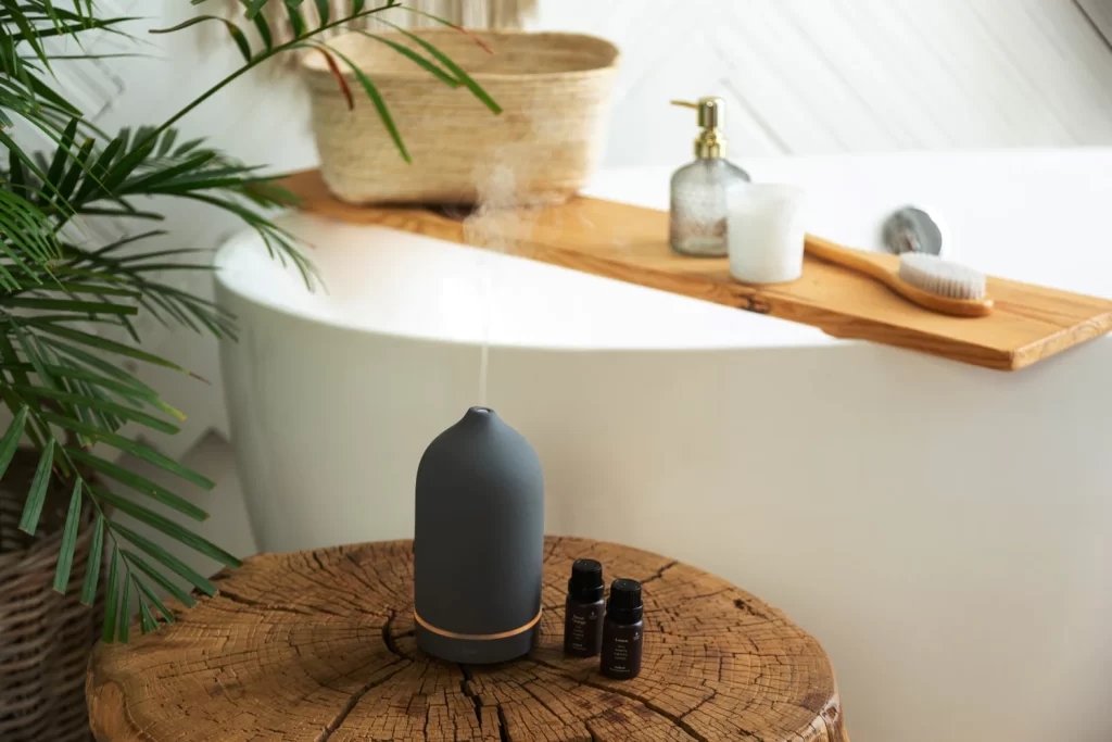 Modern spa bathroom featuring aromatherapy diffuser, freestanding bathtub, wooden accents, and indoor plants